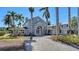 A luxurious home with a brick driveway lined with mature palm trees and manicured landscaping at 732 Siesta Dr, Sarasota, FL 34242