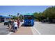The Siesta Key Frog Hop Trolley stop with people waiting to board near local shops on a sunny day at 732 Siesta Dr, Sarasota, FL 34242