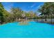 Outdoor basketball court with blue and green surface, surrounded by lush trees and a view of a lake at 7649 Quinto Dr, Sarasota, FL 34238