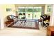 Sunlit living room features a comfortable seating area, piano, and large windows overlooking the lush backyard at 7649 Quinto Dr, Sarasota, FL 34238
