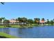 Scenic view of a tranquil pond surrounded by lush landscaping and community buildings at 8300 Jesolo Ln, Sarasota, FL 34238