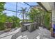 Screened patio featuring an outdoor dining table, lush greenery, and views of the lake at 8956 Stone Harbour Loop, Bradenton, FL 34212