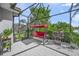 Relaxing screened patio with red swing, brick flooring, and lush greenery at 8956 Stone Harbour Loop, Bradenton, FL 34212