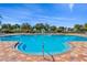 Community pool with colorful brick patio, lounge chairs, and play area under a clear blue sky at 8956 Stone Harbour Loop, Bradenton, FL 34212