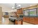 Spacious kitchen with wood cabinets, tile floors, and a large island with cooktop and black granite countertops at 940 Siesta Key Pl, Sarasota, FL 34242