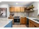 Open kitchen with stainless steel appliances, wood cabinets, floating shelves, island, and tiled backsplash at 1239 Pinebrook Way, Venice, FL 34285