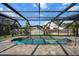 Inviting in-ground pool surrounded by a screened enclosure, with a view of the backyard and neighboring houses at 1239 Pinebrook Way, Venice, FL 34285