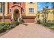 Paver driveway leads to a tan Mediterranean-style townhome with a brown garage door and manicured landscaping at 1308 3Rd Street E Cir, Palmetto, FL 34221