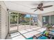 Screened-in lanai with ceiling fan overlooks a lushly landscaped backyard with a brick patio at 1565 Saturn Rd, Venice, FL 34293