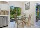 Bright eat-in kitchen area with a round glass table, view of the backyard, and stainless steel dishwasher at 1718 Starling Dr # 104, Sarasota, FL 34231