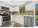 Well-equipped kitchen featuring stainless steel appliances, tile backsplash, and white cabinets with modern fixtures at 1718 Starling Dr # 104, Sarasota, FL 34231