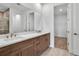 Bathroom showcasing double sink vanity with wood cabinets, gold hardware, and a large mirror at 18821 Dayspring Pl, Venice, FL 34293