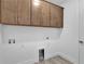 Laundry room featuring upper cabinets with gold handles, tile floor, and white walls at 18821 Dayspring Pl, Venice, FL 34293