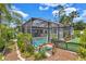 Backyard featuring a screened-in pool surrounded by tropical plants and decorative accents at 2625 Yuma Ave, North Port, FL 34286
