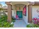 Inviting front porch with decorative columns, a colorful door, and a whimsical pink chair at 2625 Yuma Ave, North Port, FL 34286