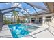 In-ground pool with sunny screened-in lanai features, patio dining area and lush landscaping at 2625 Yuma Ave, North Port, FL 34286