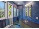 Modern bathroom featuring blue tiled walls, glass shower, and view to the outdoors from the window at 2828 Riverview Blvd, Bradenton, FL 34205
