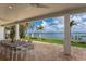 Covered patio with comfortable outdoor seating, overlooking a landscaped backyard and picturesque waterfront at 2828 Riverview Blvd, Bradenton, FL 34205