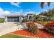 Beautifully landscaped home with a well-manicured lawn, mature trees, and a spacious driveway leading to a two-car garage at 292 Long Meadow Ln, Rotonda West, FL 33947
