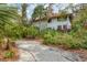 Exterior view of a two story home with a gravel drive surrounded by lush, mature landscaping at 3330 Thornwood Rd # 3330, Sarasota, FL 34231