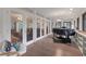 Sunroom with floor to ceiling glass doors showing the living room with grand piano and bookshelves at 3330 Thornwood Rd # 3330, Sarasota, FL 34231