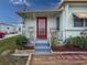 Charming home featuring a red door, small deck, and front yard with colorful flowers and tropical plants at 4103 12Th Street E Ct, Ellenton, FL 34222