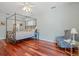 Bedroom featuring wood floors, four-poster bed, and a stylish accent chair at 4117 Roberts Point Cir, Sarasota, FL 34242