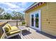 Relax on the deck with comfortable seating near the door to the bright yellow home at 4117 Roberts Point Cir, Sarasota, FL 34242