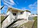 Beige mobile home featuring a small covered patio and an A/C unit on a grass lawn at 415 Oakwood E Blvd, Sarasota, FL 34237