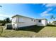 Beige mobile home featuring window awnings and an A/C unit sitting on a grass lawn at 415 Oakwood E Blvd, Sarasota, FL 34237