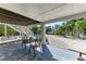 Covered patio area with seating, offering shade and views of the pool, landscaping, and waterfront at 526 Loquat Dr, Anna Maria, FL 34216