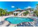 Backyard with a sparkling blue pool, landscaped with white stone, pavers, and tropical palm trees at 526 Loquat Dr, Anna Maria, FL 34216