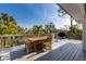 Outdoor deck featuring a wooden dining table, a grill, and nice views of the tropical plants nearby at 527 Magnolia Ave, Anna Maria, FL 34216