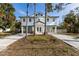 Inviting elevated home featuring a white exterior and a blue roofline, complemented by well-maintained landscaping at 527 Magnolia Ave, Anna Maria, FL 34216