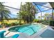 Sparkling pool surrounded by a screened enclosure, tropical plants, and blue seating at 573 Misty Pine Dr, Venice, FL 34292