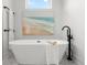 Freestanding tub with black faucet, white towels and beach themed art at 597 Buttonwood Dr, Longboat Key, FL 34228