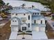 Elegant white home featuring a metal roof, a multi-car garage, and landscaped front yard at 597 Buttonwood Dr, Longboat Key, FL 34228