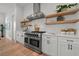Modern kitchen showcasing stainless steel appliances, white cabinetry, open shelving, and hardwood floors for a contemporary feel at 597 Buttonwood Dr, Longboat Key, FL 34228