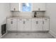 Bright laundry room featuring white cabinets, light countertops, undermount sink, modern faucet and tile floor at 597 Buttonwood Dr, Longboat Key, FL 34228