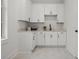 Well-lit laundry room with white cabinetry, quartz countertops, and modern fixtures at 597 Buttonwood Dr, Longboat Key, FL 34228