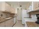 Functional kitchen with a white sink, neutral cabinetry, granite countertops, and standard appliances at 602 Casa Del Lago Way # 602, Venice, FL 34292