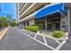 Building entrance with blue awning, well-maintained landscaping, and visible parking area at 6415 Midnight Pass Rd # 211, Sarasota, FL 34242
