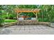 Outdoor kitchen with a grill, stone counters, a pergola, and a view of the lush landscaping at 6415 Midnight Pass Rd # 211, Sarasota, FL 34242
