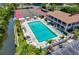 An aerial view of a large pool with lounge chairs, umbrellas, and a tennis court in the background at 6415 Midnight Pass Rd # 211, Sarasota, FL 34242