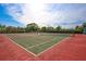 Well-maintained tennis court with lush landscaping, a green and red surface, and a net at 6415 Midnight Pass Rd # 211, Sarasota, FL 34242