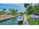 Scenic waterfront view with boat docked along canal, lush landscaping, and building in the background at 6415 Midnight Pass Rd # 211, Sarasota, FL 34242