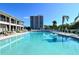 Large community pool with lounge chairs, umbrellas, and a view of the condo buildings at 6415 Midnight Pass Rd # 910, Sarasota, FL 34242