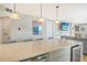 Kitchen island with marble countertop, pendant lights, stainless steel appliances, and a view of the living area at 6415 Midnight Pass Rd # 910, Sarasota, FL 34242
