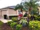 Landscaped front yard with well-maintained lawn, shrubs, and palm trees enhances curb appeal of this tan-colored home at 6916 Stoneywalk Ct # 6916, Bradenton, FL 34203