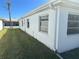 Side exterior view of a white house, showcasing its clean lines, windows, and well-maintained lawn under a clear blue sky at 699 El Centro # 699, Longboat Key, FL 34228